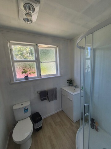 The completed bathroom - a new vanity, glass shower, modern toilet and fresh timber-look flooring